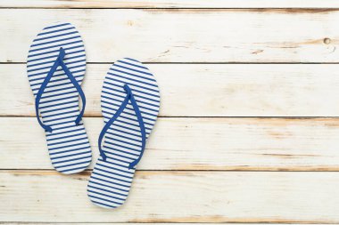 Ahşap arka planda çizgili mavi parmak arası terlikler, üst görünüm
