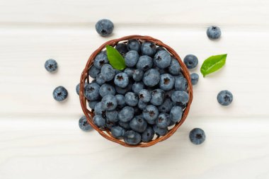 Ahşap arka planda taze yaban mersinli kase, üst manzara.