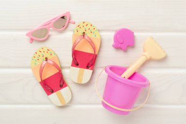 Çocuk terlikleri ve tahta arka planda plaj oyuncakları, üst manzara.