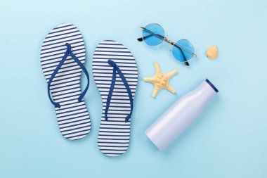 Renkli arka planda aksesuarları olan çizgili mavi parmak arası terlikler, üst görünüm