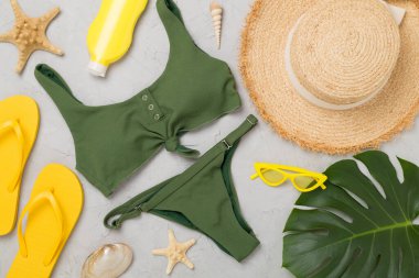 Beton arka planda renkli plaj aksesuarlarıyla yatıyordu. Tatil kavramı