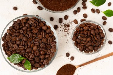 Beton arka planda yaprakları olan kavrulmuş kahve çekirdekleri.