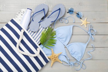 Ahşap arka planda plaj aksesuarları olan mavi bikini.