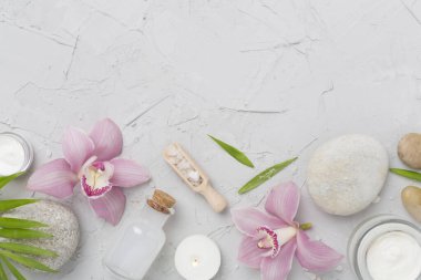 Beton zemin üzerinde orkideler ve masaj taşları olan kompozisyon, üst görünüm