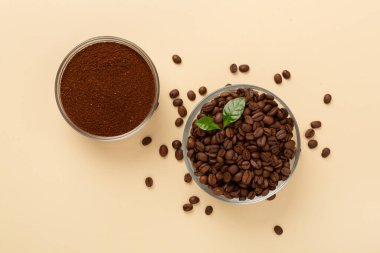 Arka planda yaprakları olan kavrulmuş kahve çekirdekleri.