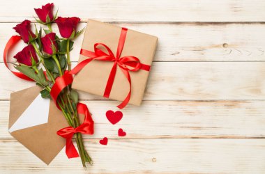 Ahşap arka planda hediye kutusu olan kırmızı gül çiçekleri, üst, manzara. Sevgililer Günü konsepti