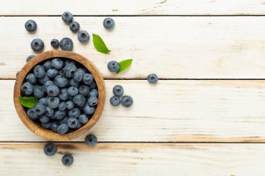 Ahşap arka planda taze yaban mersinli kase, üst manzara.