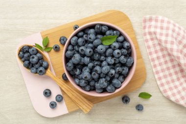 Ahşap arka planda taze yaban mersinli kase, üst manzara.