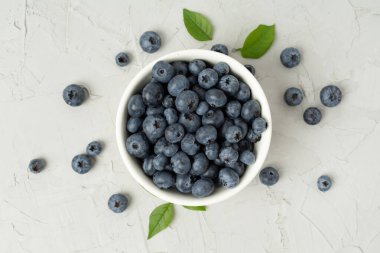 Beton arka planda taze yaban mersinli kase, üst manzara.