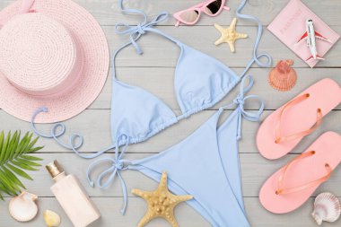 Ahşap arka planda plaj aksesuarları olan mavi bikini.