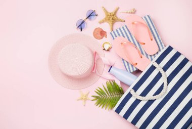 Renkli arka planda yaz aksesuarları olan mavi plaj çantası, üst manzara.