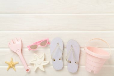 Çocuk terlikleri ve tahta arka planda plaj oyuncakları, üst manzara.