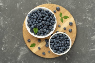 Beton arka planda taze yaban mersinli kase, üst manzara.