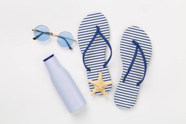 Renkli arka planda aksesuarları olan çizgili mavi parmak arası terlikler, üst görünüm