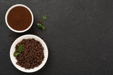 Beton arka planda yaprakları olan kavrulmuş kahve çekirdekleri.