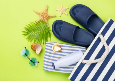 Renkli arka planda yaz aksesuarları olan mavi plaj çantası, üst manzara.