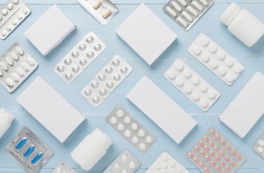 Su toplamada ve kutularda farklı haplar ve ahşap arka planda üst görünüm.