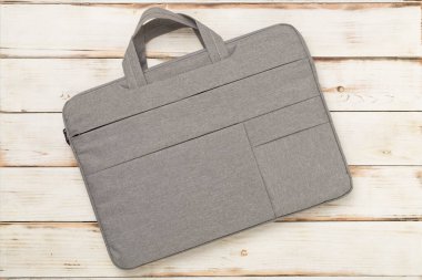 Ahşap arka planda gri renkli dizüstü bilgisayar çantası.