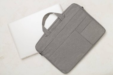 Beton zemin üzerinde aygıt bulunan gri renkli dizüstü bilgisayar çantası, üst görünüm