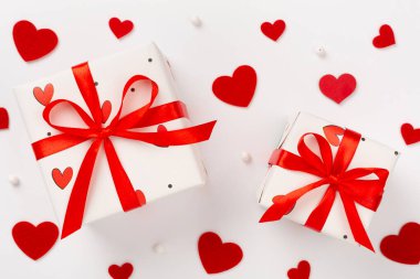 Renk arkaplanında kırmızı kalpler olan bayramlık hediye kutuları, üst görünüm