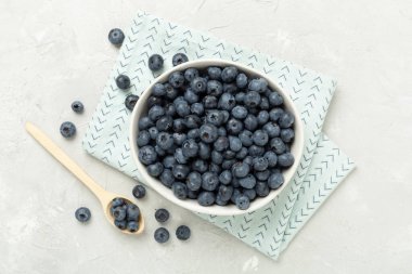 Beton arka planda taze yaban mersinli kase, üst manzara.