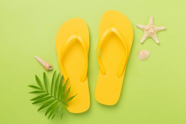 Renkli arka planda parlak sarı parmak arası terlikler, üst manzara. Yaz konsepti