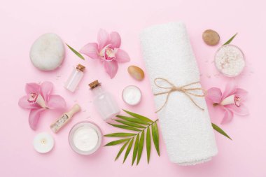 Orkideli kompozisyon, renk arkaplanlı spa ürünleri, üst görünüm