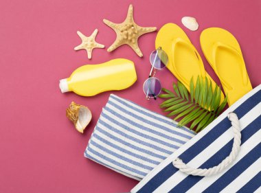 Renkli arka planda yaz aksesuarları olan mavi plaj çantası, üst manzara.