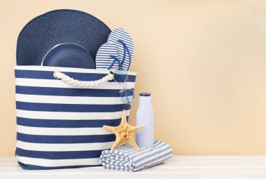 Mavi kumsal çantası ve ahşap masa üzerinde yaz aksesuarları.