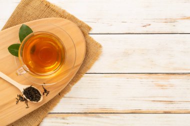 Tahta arka planda kuru ve taze yapraklı bir fincan çay, üst manzara.