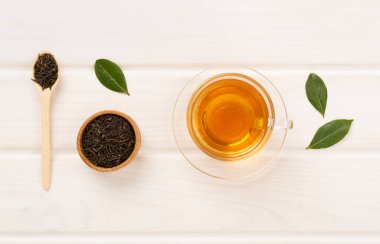 Tahta arka planda kuru ve taze yapraklı bir fincan çay, üst manzara.