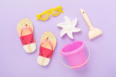 Çocuk terlikleri ve arka planda plaj oyuncakları, üst manzara.