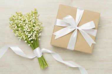 Ahşap arka planda hediye kutusuyla vadideki zambaklar.