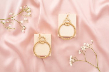 Tekstil arka planında süslemeleri olan zarif altın mücevherler.