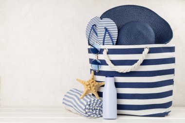 Mavi kumsal çantası ve ahşap masa üzerinde yaz aksesuarları.