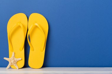 Masada parlak sarı parmak arası terlikler. Yaz konsepti