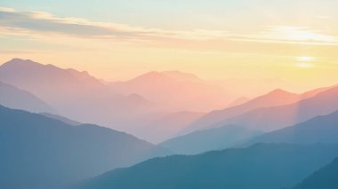 Sakin dağ siluetlerinin nefes kesici gün doğumuna ya da günbatımına karşı yapılan nefes kesici güzelliğini tecrübe edin. Bu çarpıcı manzara fotoğrafı, ufukta mavi, pembe, turuncu ve sarı renkli yumuşak pastel renkler sergiliyor.