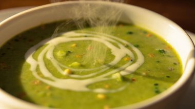 Kırsal bir kasede lezzetli, kremalı yeşil sebze çorbasının yakın plan çekimi. Sağlıklı beslenme, vegan / vejetaryen tarifleri veya restoran menüleri için mükemmel bir örnektir. Canlı yeşil renk ve kremsi doku vurgulanır, iştah açıcıdır.