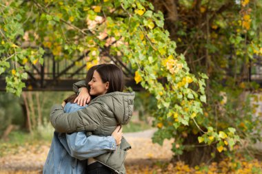 Bir sonbahar günü parkta kucaklaşan genç bir çift..