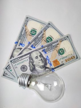 Beyaz arka planda 300 dolarlık banknotlar ve ampuller. Amerikan parası. Elektrik fiyatları. Kapat. 
