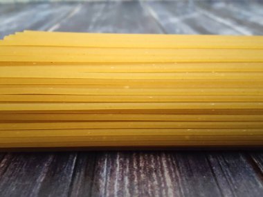 Tahta bir masada çiğ spagetti. İtalyan makarnası için ana malzeme. Makro fotoğrafçılık 