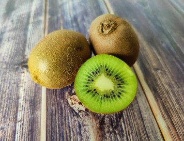 İki tam kivi ve yarım. Tahta bir masada tropik yeşil meyve. Kapat. 