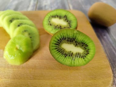 Tahta bir tahtanın üzerine kesilmiş kivi tropikal meyveler. Yakın plan.