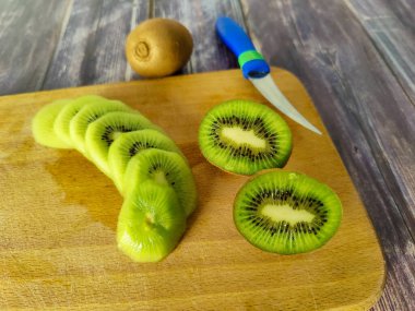 Tahta bir tahtanın üzerine kesilmiş kivi tropikal meyveler. Yakın plan.