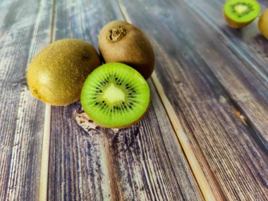 İki tam kivi ve yarım. Tahta bir masada tropik yeşil meyve. Kapat. 