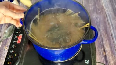 Bir tencerede spagetti haşlıyorum. Soba pişiriyorum. Bolonez pişiriyorum.