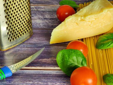 Çiğ spagetti, kiraz domatesleri, ıspanak yaprakları ve ahşap bir masada parmesan peyniri. Kapat. 