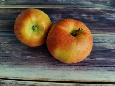 Two whole red apple on a wooden table close-up