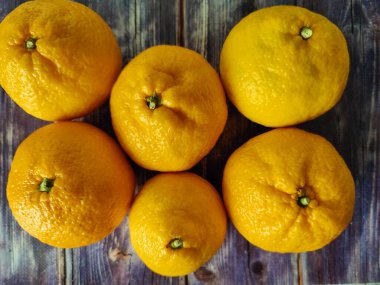 Whole tangerine and slices of peeled citrus around on wooden background. Close up 
