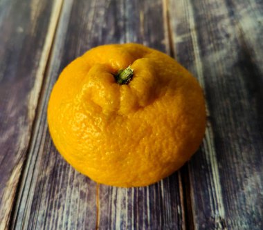 Whole tangerine and slices of peeled citrus around on wooden background. Close up 